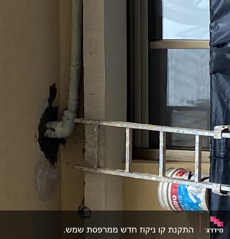 סולם מתכת ליד צינור מים על קיר חיצוני